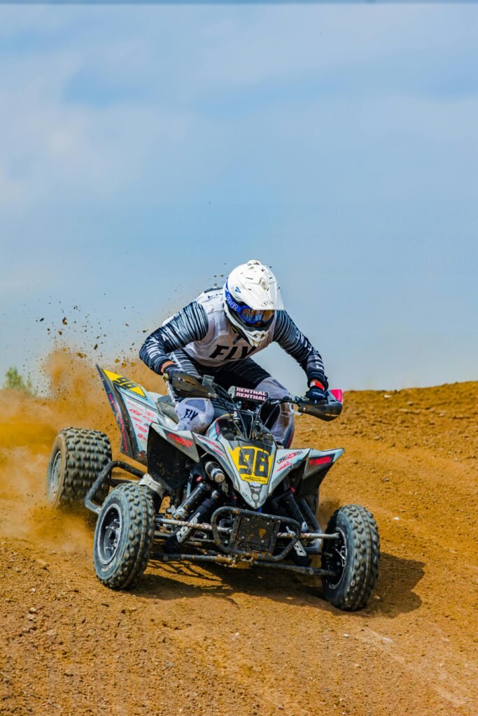 Capture of a man racing a quad bike on a sandy track, showing dynamic motion and excitement.